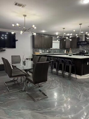 A modern kitchen with a central island, dark cabinetry, and a marble floor. - Charming 2bd 3bth house in pleasant Atlanta perfect for your next getaway! (Atlanta)