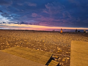 A rocky beach with a wooden walkway leading to the water. - Vrbo Property (Batumi)