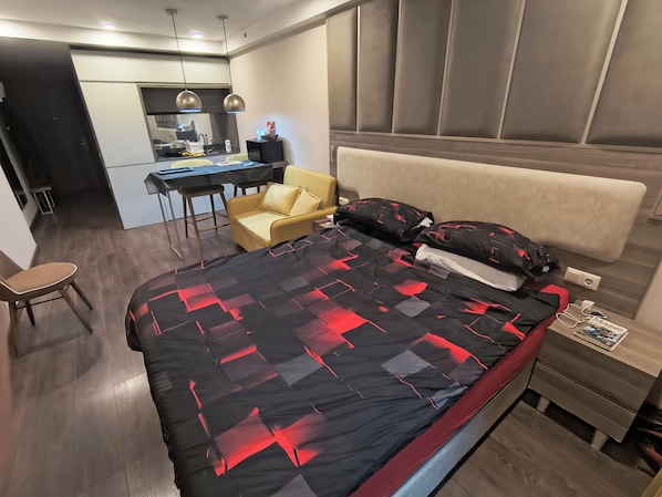A modern bedroom with a bed, bedside table, and a small desk area. - Vrbo Property (Batumi)