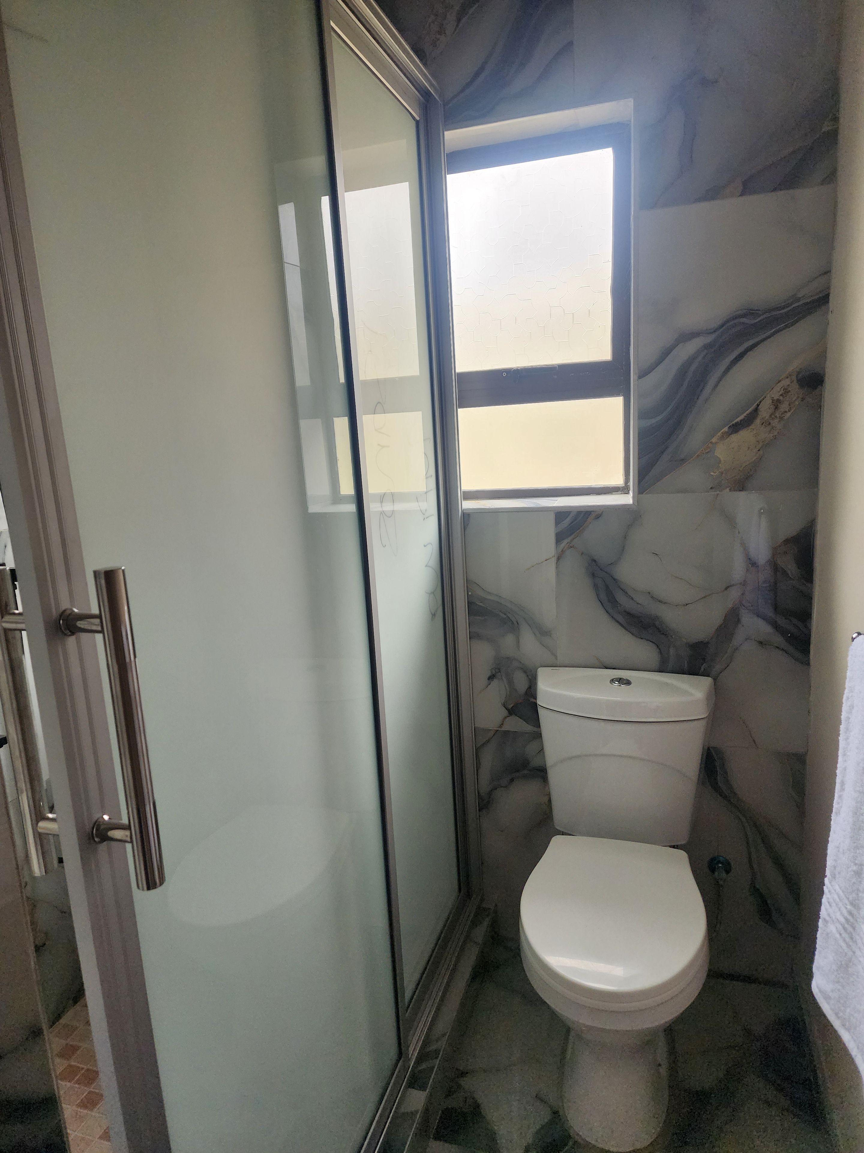 Ein Badezimmer mit Duschkabine, Toilette und Fenster.
