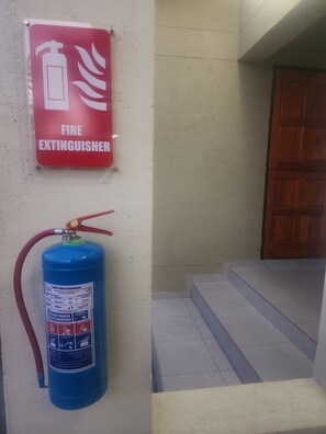 A fire extinguisher mounted on a wall with a red sign above it.