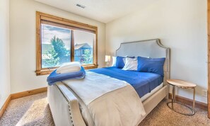 A bedroom with a large bed, a window, a bedside table, and a view of the outdoors. - Luxury Pet Friendly 4-bed PC Ski & Lake House (Wasatch County)