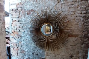 A sunburst mirror on a brick wall. - Biennale Pano-view (Venice)