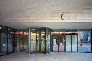 A revolving door entrance with glass panels, a sign above indicating it's a project by Fondazione Di Venezia, and a tiled floor. - Sunlit-balcony (Mestre)