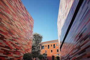 A narrow alleyway between two buildings with a clear blue sky above. - Sunlit-balcony (Mestre)