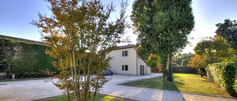 A house with a paved driveway, a lawn, and a tree in the foreground.