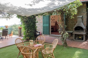 An outdoor patio with wicker chairs, a table, and a grill area. - Alassio-villa-sea-view (Alassio)