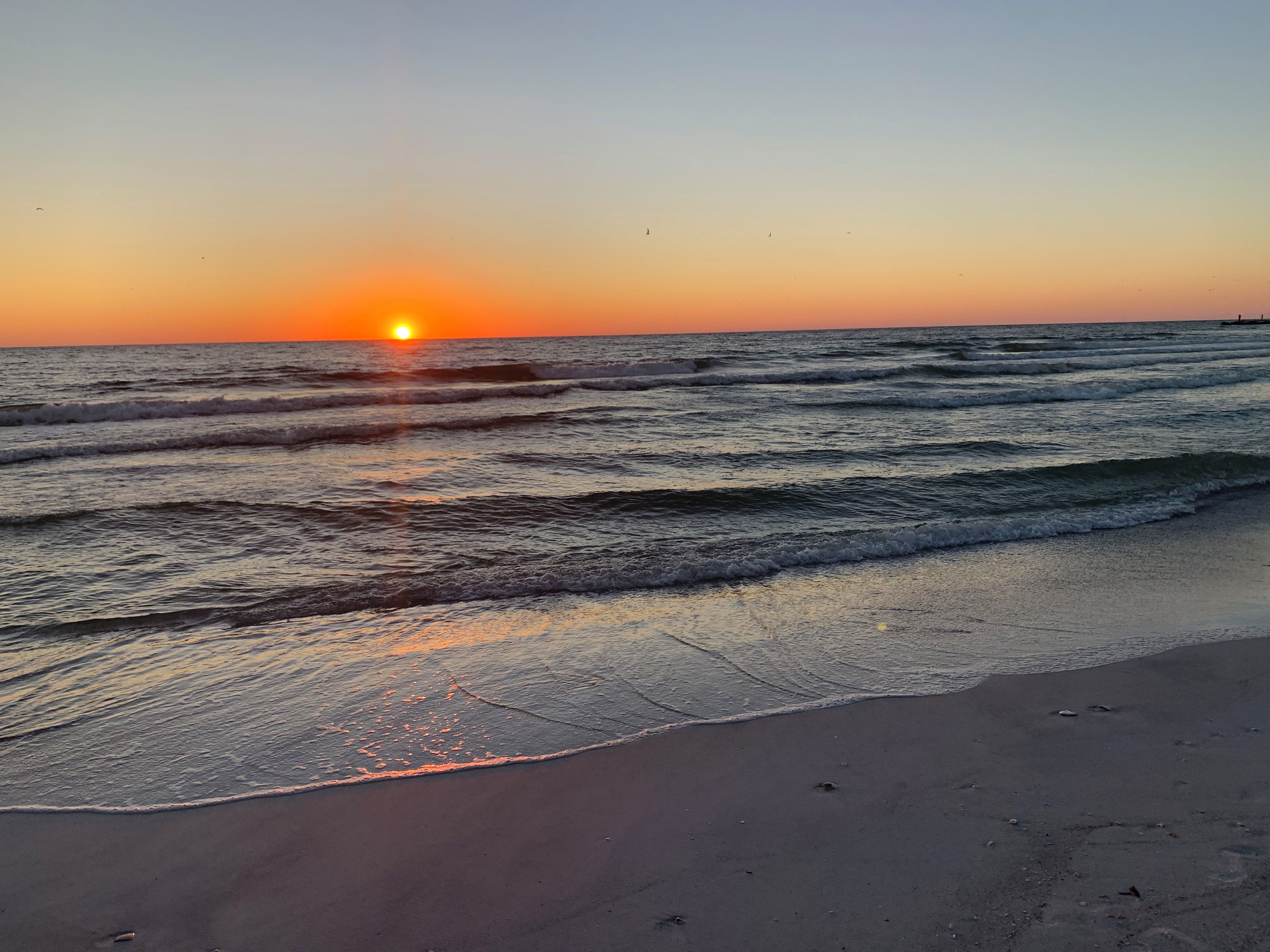 Een strand met golven en een zonsondergang.