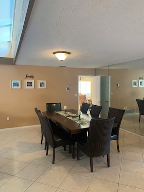 A dining area with a long table, chairs, and a ceiling light fixture. - 3-bedroom house on canal, gated community, private beach access on Longboat Key! (Longboat Key)