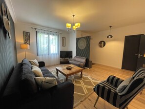 A living room with a sofa, armchair, coffee table, TV, and decorative wall art. - La Closerie (La Redorte)