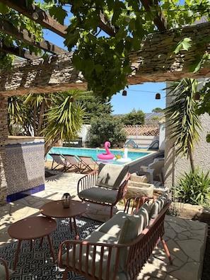 A poolside area with a stone wall, a pool, lounge chairs, and a flamingo float. - La Closerie (La Redorte)