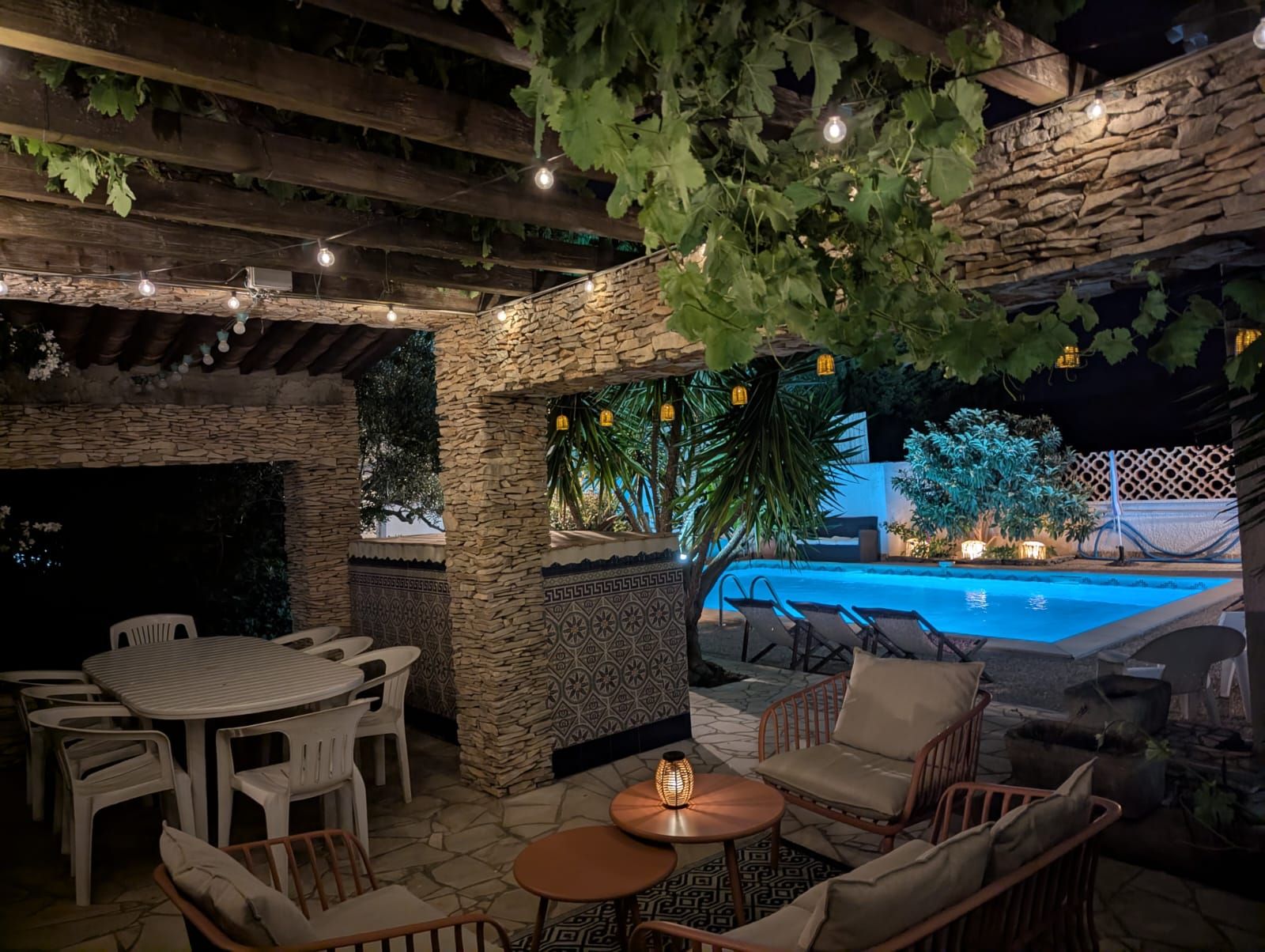 An outdoor patio with stone walls, a pool, and seating arrangements.