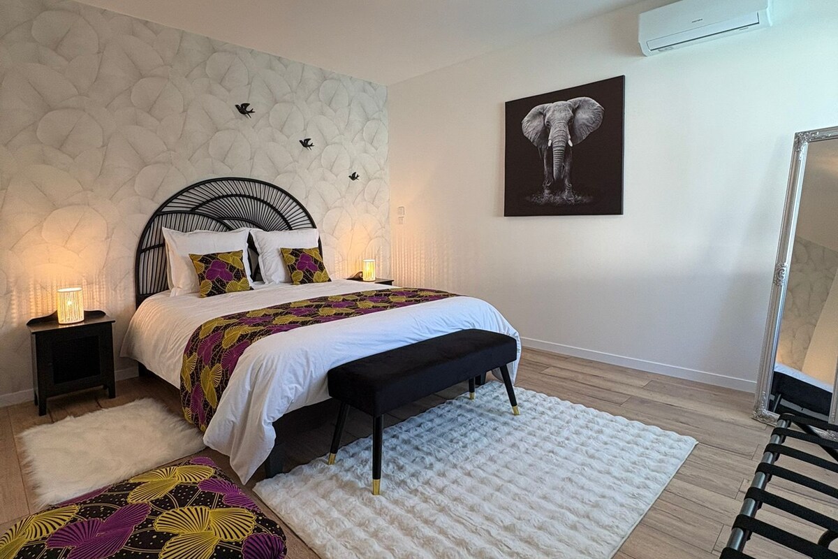 Un dormitorio con cama, mesitas de noche, un banco, un tapete y un aire acondicionado de pared.