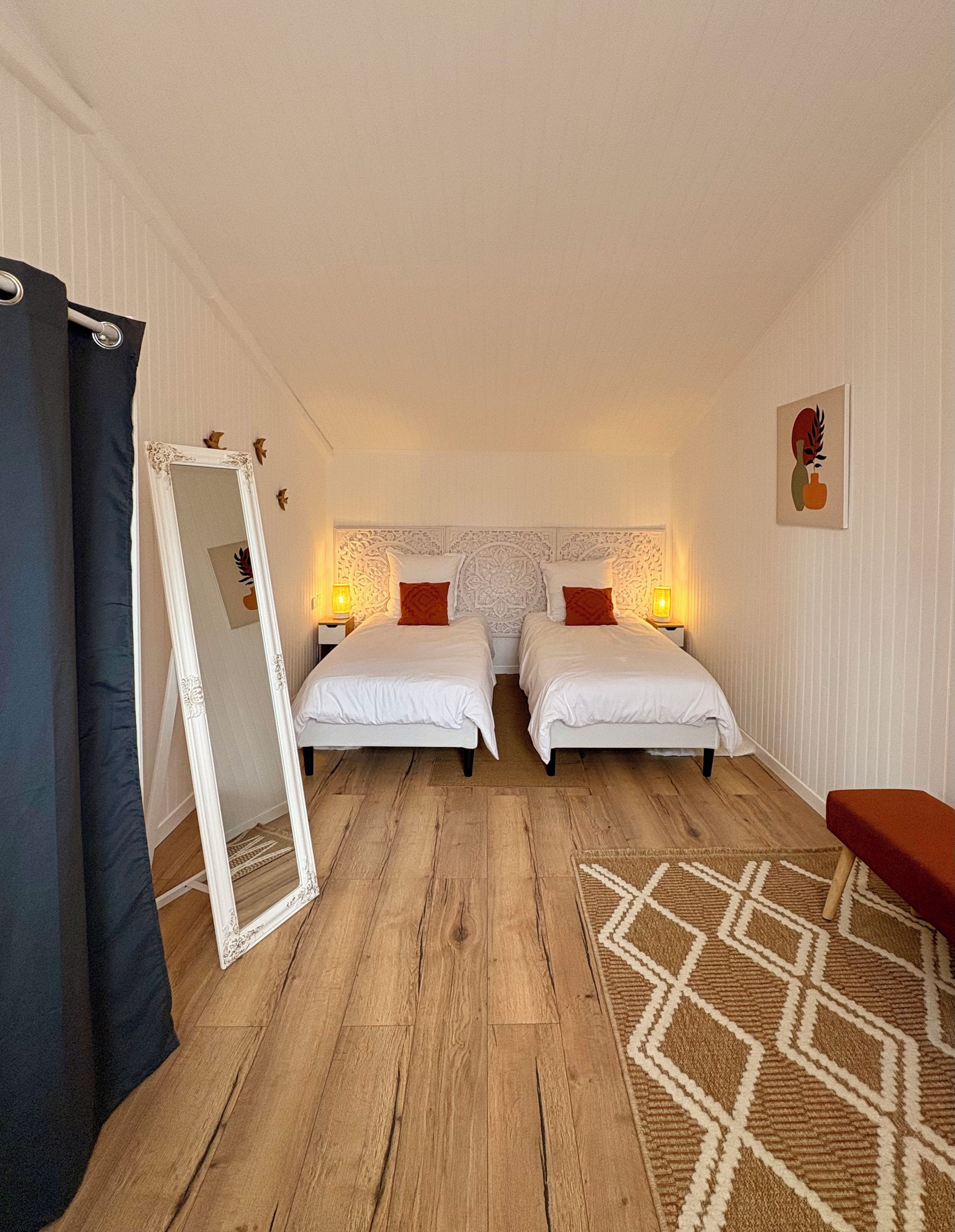 Een hotelkamer met twee bedden, een grote spiegel, een kamerkleed met een patroon en een kleine tafel.