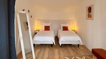 Een hotelkamer met twee bedden, een grote spiegel, een kamerkleed met een patroon en een kleine tafel.