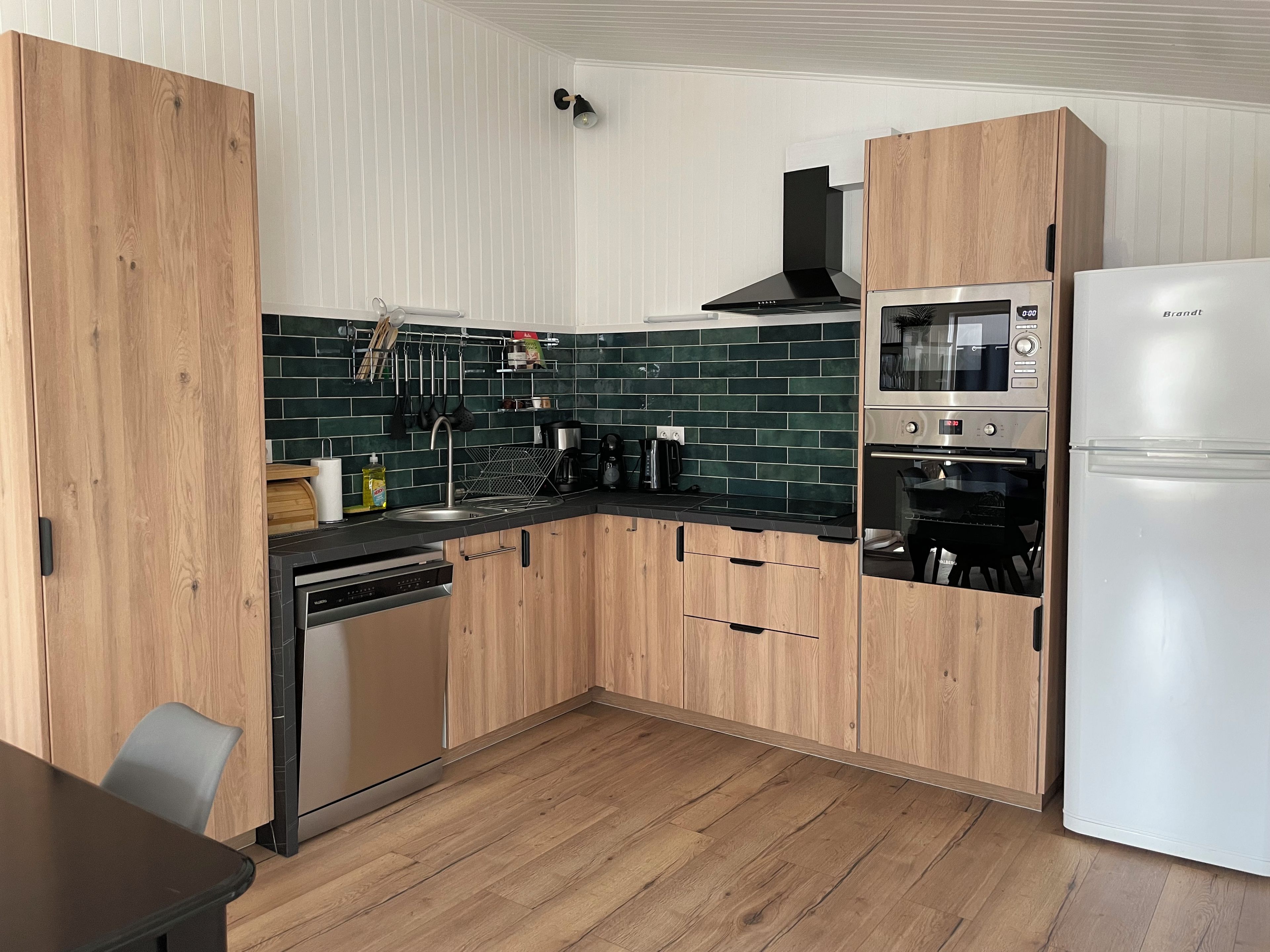 A modern kitchen with wooden cabinets, a stainless steel sink, and a built-in oven.