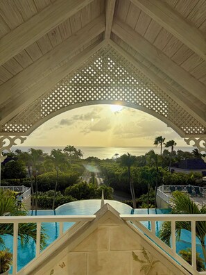 Zona de piscina con vista al océano y palmeras.