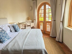 Un dormitorio con cama, cómoda, ventana con cortinas y vistas al exterior.