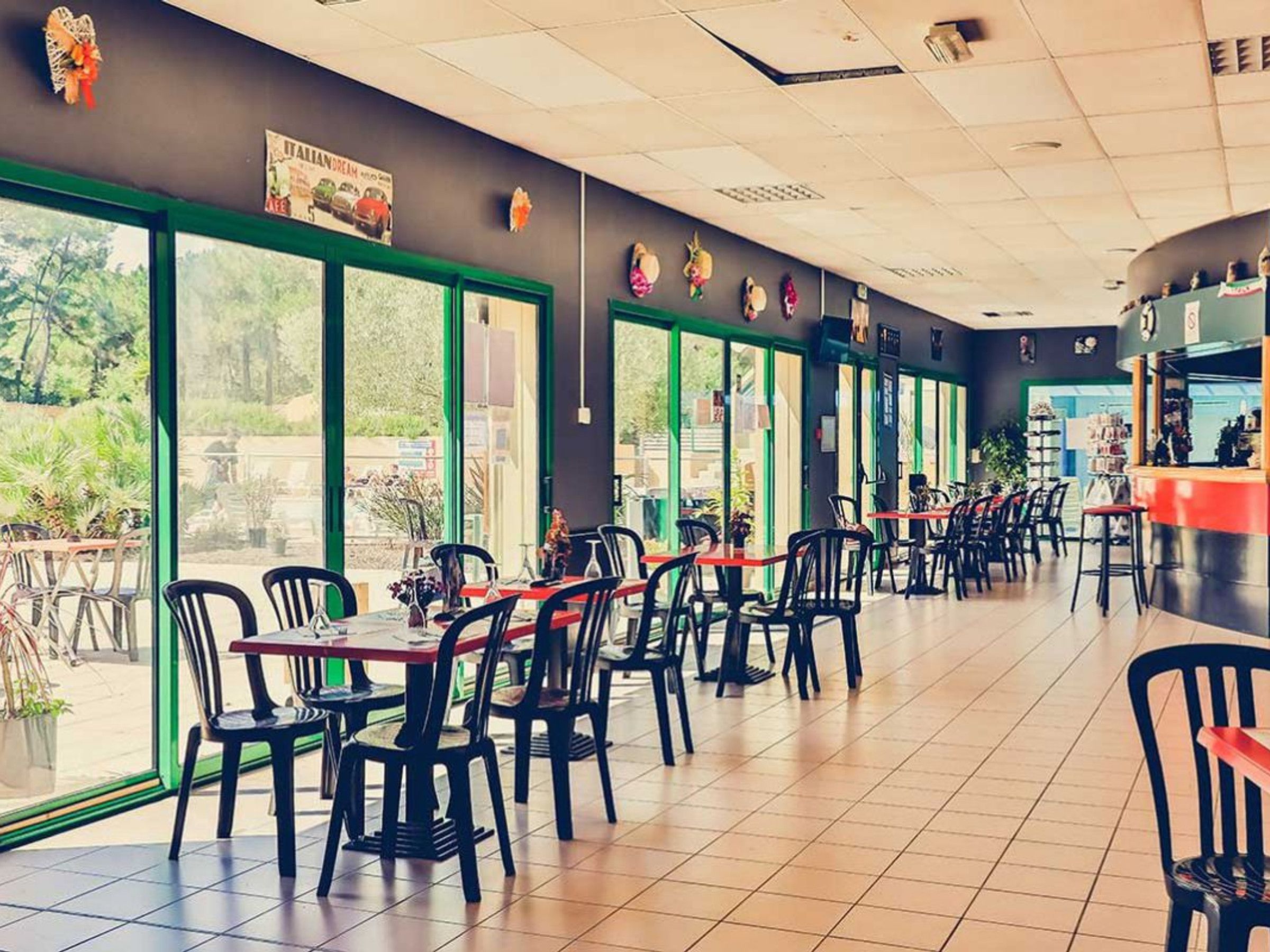 Un restaurante con mesas en el interior, ventanas amplias y una zona de mostrador.