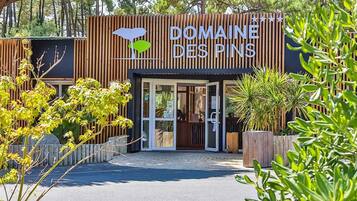 A hotel entrance with a wooden facade and a sign that reads 'Domaine des Pins'.