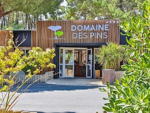 Ein Hotel Eingang mit einer Holzfassade und einem Schild mit der Aufschrift 'Domaine des Pins'.