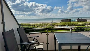 A balcony with a table and chairs overlooking a beach.