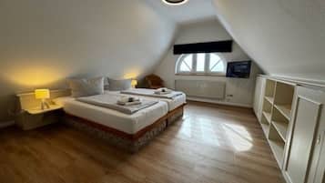A bedroom with two beds, a nightstand, a window, and built-in shelving.