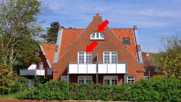 A traditional brick house with a gabled roof, a central chimney, and a front entrance with a white door.