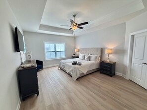 Una camera da letto con un letto, comodini, una ventola a soffitto, una finestra e una porta.