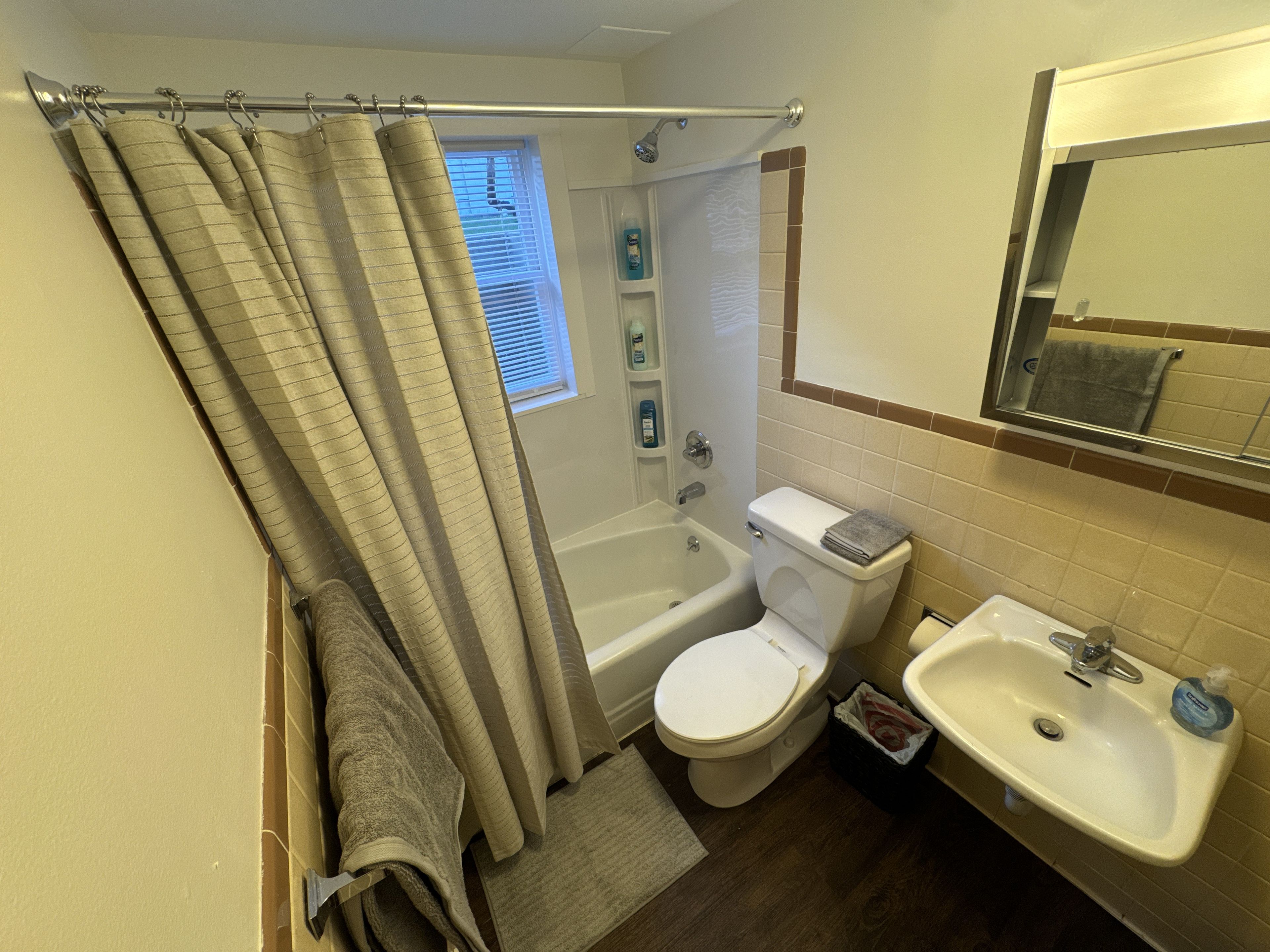Une salle de bain équipée d’une baignoire, de toilettes, d’un lavabo et d’une pomme de douche.