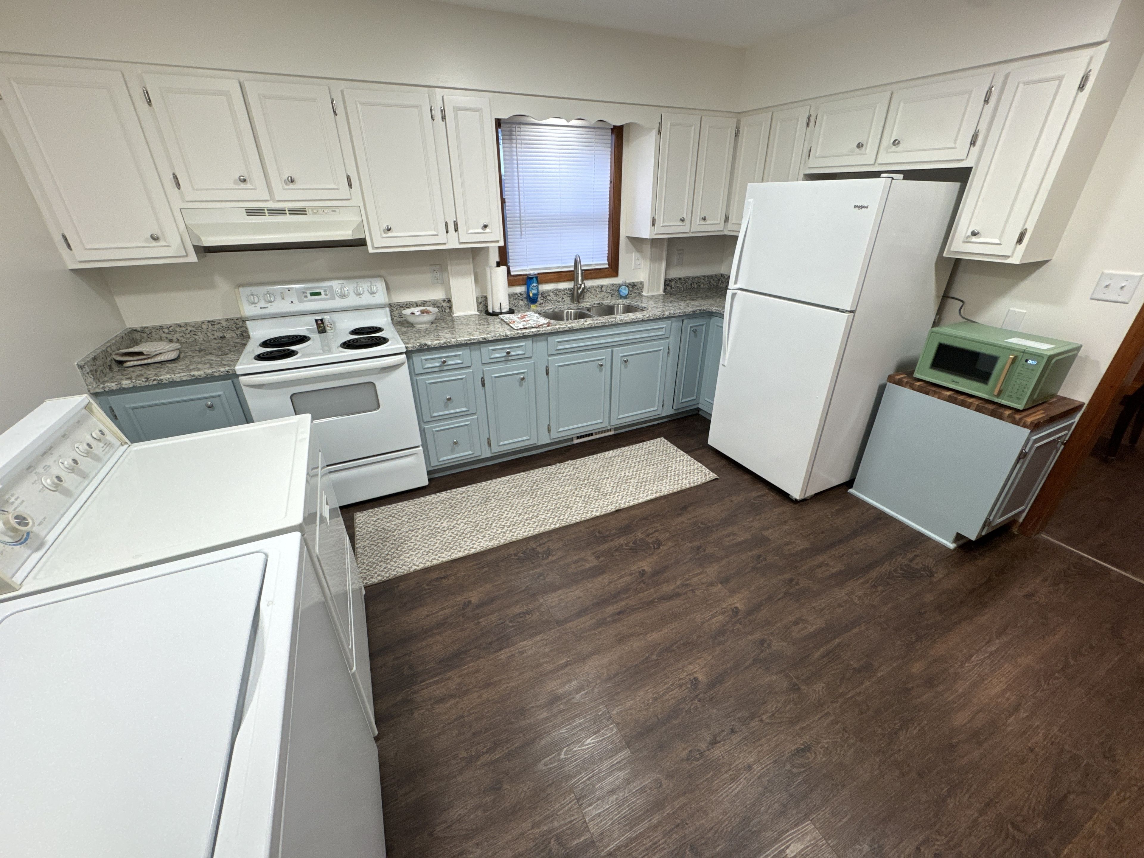 A kitchen with white cabinets, a stove, a refrigerator, and a microwave.