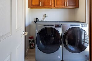 Two front-loading washing machines in a laundry room with wooden cabinets above. - Beautiful 3BR Home in La Mesa\ Spacious & Comfortable (La Mesa)