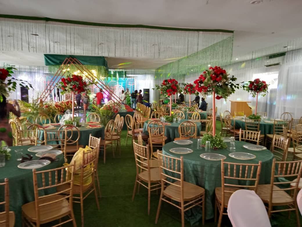 A banquet hall with round tables, chairs, and floral centerpieces.