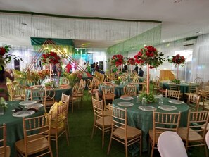 Un salón de banquetes con mesas redondas, sillas y centros de mesa con flores.