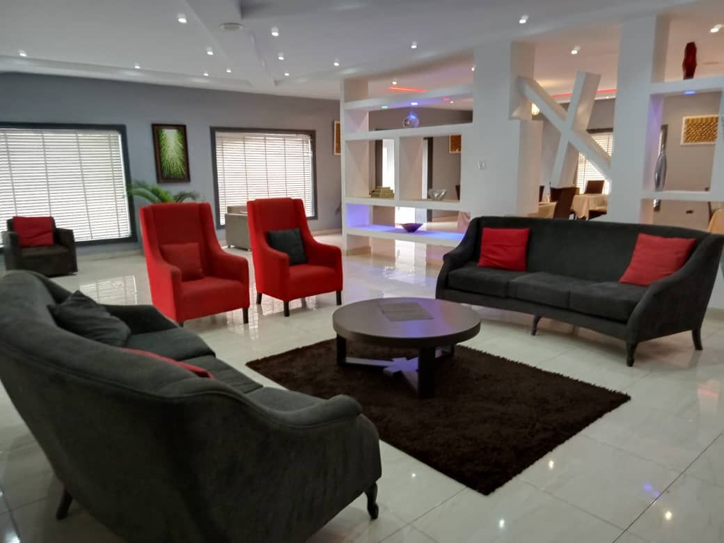 Una sala de estar moderna con un sofá, sillones, una mesa de centro y una escalera que sube a un nivel superior.