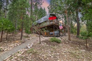 A cabin with a wooden deck, a staircase, and an American flag. - Tahoe Retreat with Hot Tub in Carnelian Bay (Carnelian Bay)