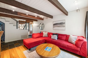A modern living room with a red sectional sofa, a wooden coffee table, and a staircase leading to another level. - Tahoe Retreat with Hot Tub in Carnelian Bay (Carnelian Bay)