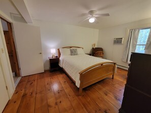 A bedroom with a wooden bed, a nightstand, a ceiling fan, and a window with curtains. - Peaceful 1-bedroom apartment 
12 min from Manchester & Close to Ski Mountains (Arlington)