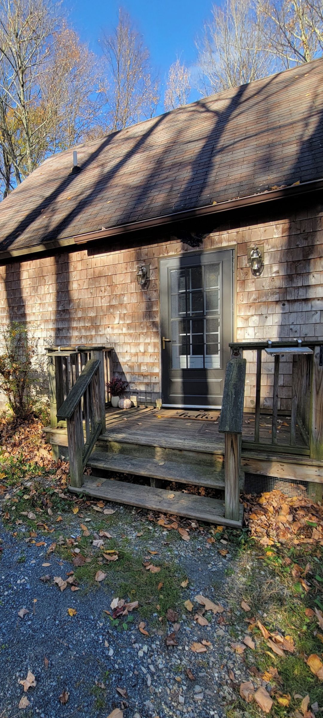 A rustic building with a wooden porch, a door with glass panels, and a small outdoor seating area.
