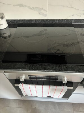 A kitchen with a Bosch induction cooktop, a stainless steel range hood, and a tiled backsplash. - Short Stay Experts A3 - E1 Studio  8 floor apartment (Gibraltar)