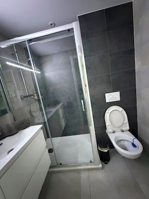 A modern bathroom with a glass-enclosed shower, a white toilet, and a white sink. - Short Stay Experts A3 - E1 Studio  8 floor apartment (Gibraltar)