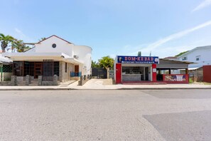 A street view with a modern two-story building and a small food kiosk. - Modern Sosua APT Near Beaches and Cafe (Sosúa)