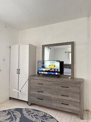 A room with a white wardrobe, a wooden dresser with drawers, a flat-screen TV on top, and a mirror above the dresser. - 2-bedroom apartment in adorable Arecibo with AC for relaxing stays (Arecibo)