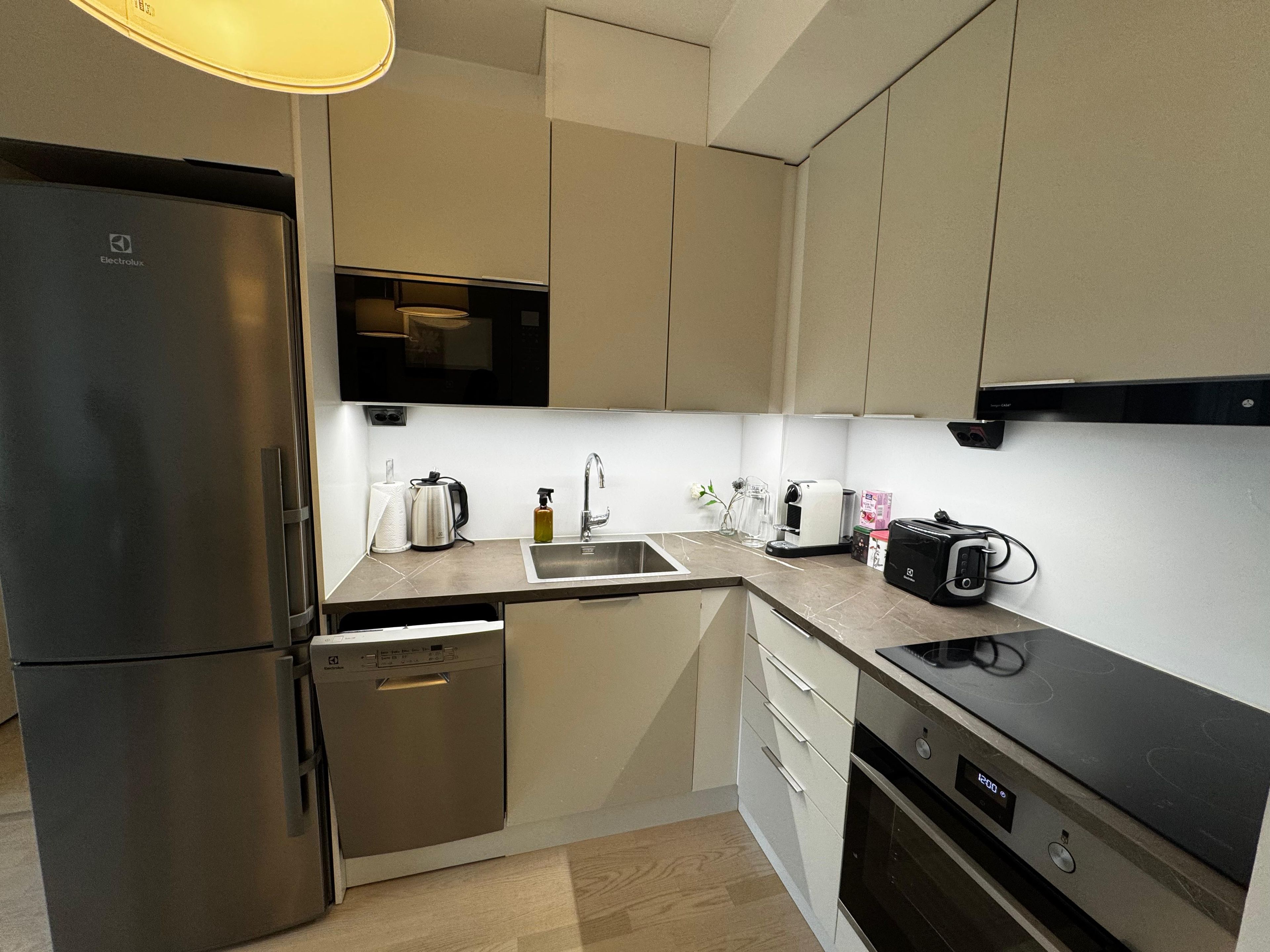 Eine moderne Küche mit Kühlschrank, Geschirrspüler, Mikrowelle, Toaster und Spüle.
