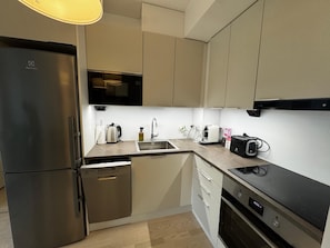 A modern kitchen with a refrigerator, dishwasher, microwave, toaster, and sink.