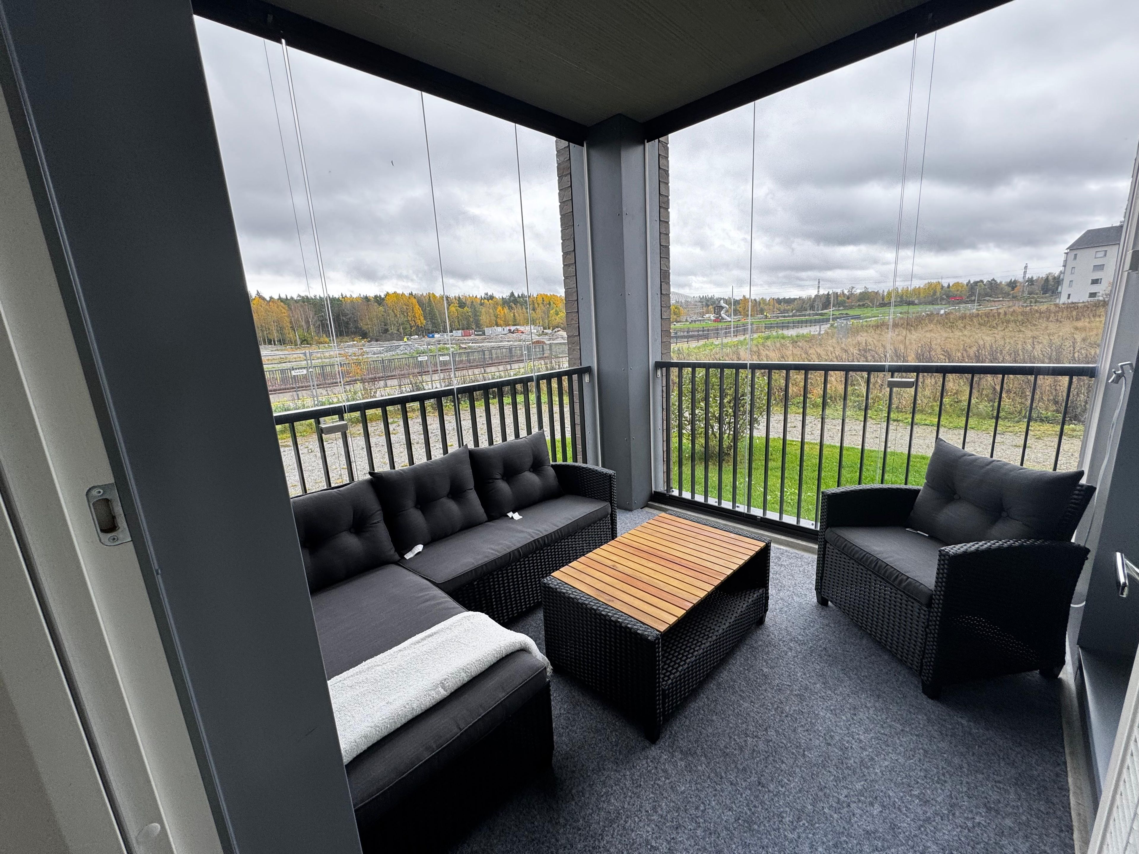 Een balkon met een bank, een klein tafeltje en rieten stoelen.