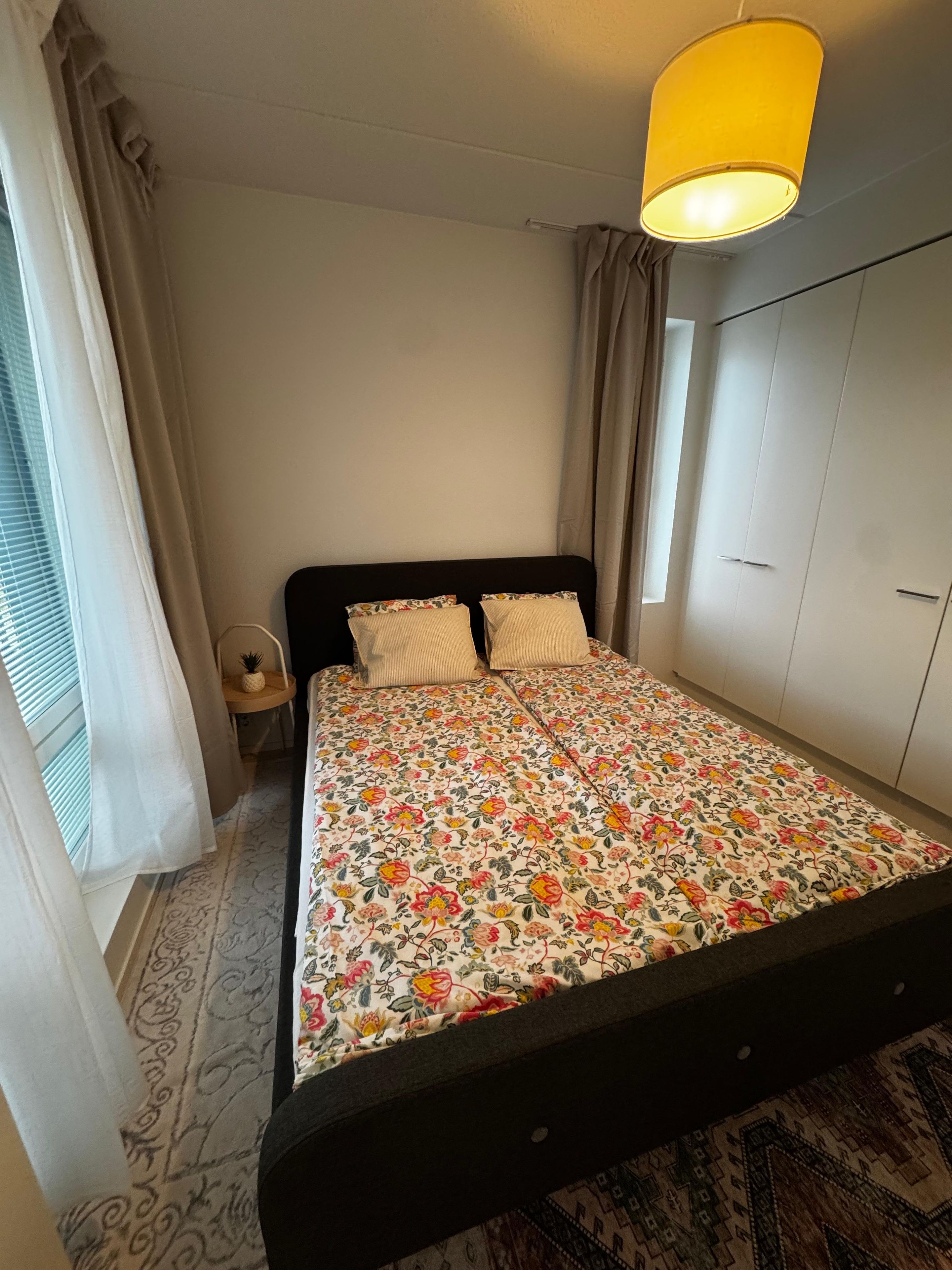 A bedroom with a bed, a nightstand, a lamp, and a wardrobe.