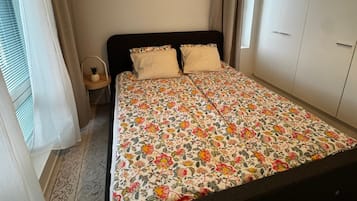 A bedroom with a bed, a nightstand, a lamp, and a wardrobe.
