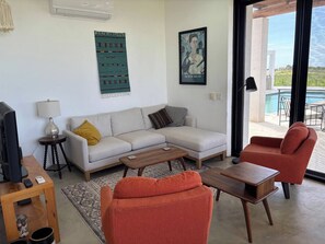 A living room with a sofa, armchairs, a coffee table, a TV, and a painting. - One bedroom casita with pool and ocean views (Todos Santos)