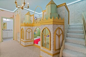 Een kinderkamer ingericht als kasteel, met een bed, een trap en een badkamer.